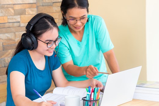 Mother helping daughter on laptop