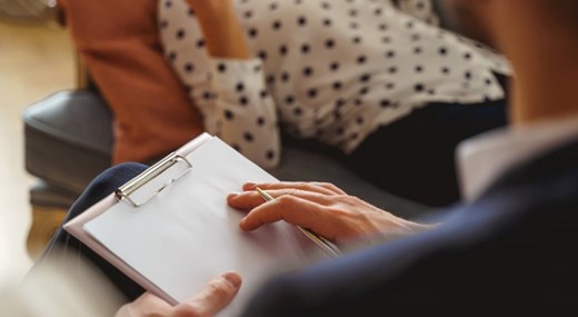 Woman lying on couch with therapist holding clipboard